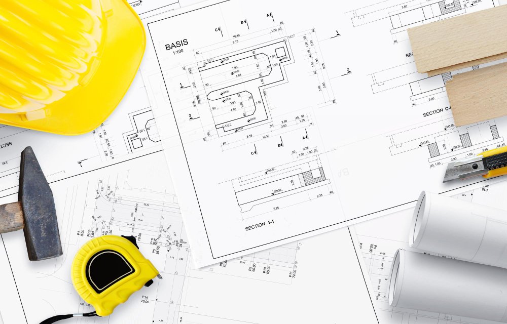 MEP Design Construction blueprint plans with yellow hard hat and tape measure