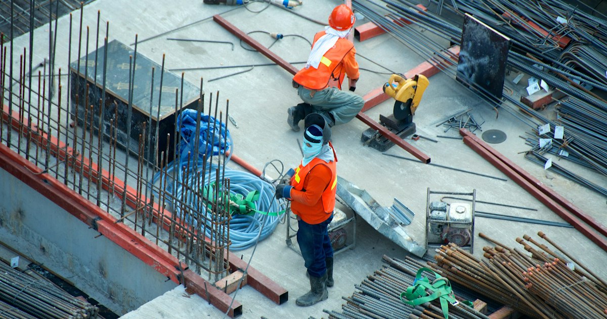 Construction engineers reviewing blueprints at a building site with structural framework in the background