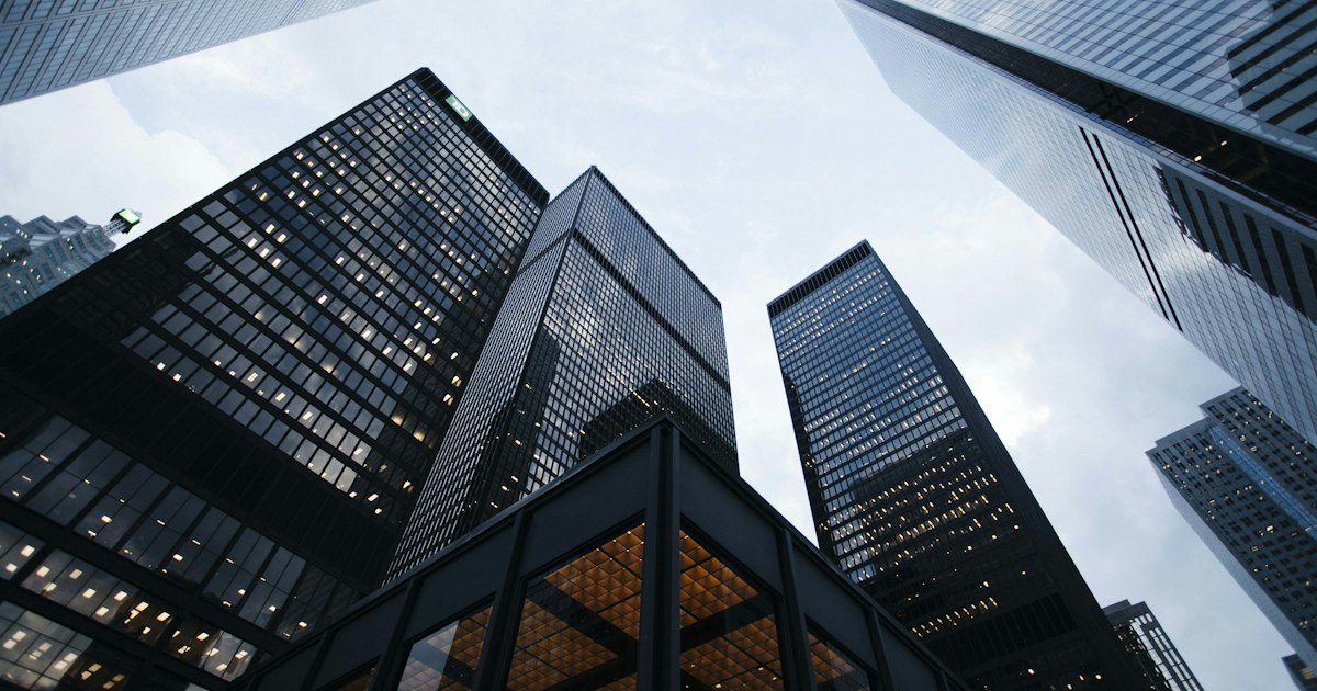 Modern glass commercial office building facade reflecting daylight, representing energy-efficient building design