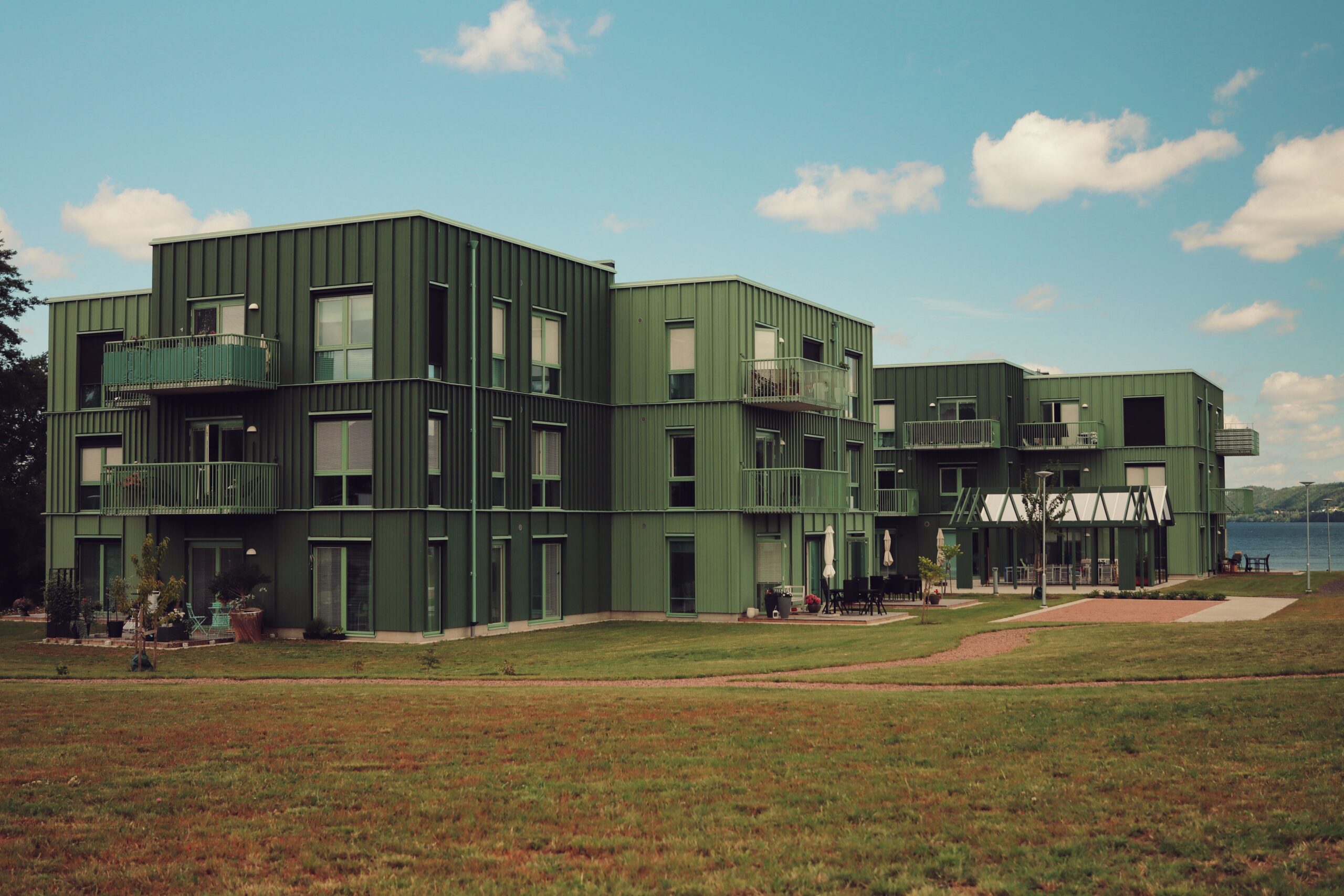 Modern green residential buildings beside water under a bright sky