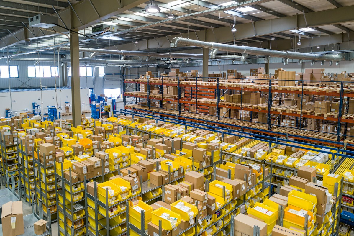 Large industrial warehouse interior with tall pallet racking and a worker
