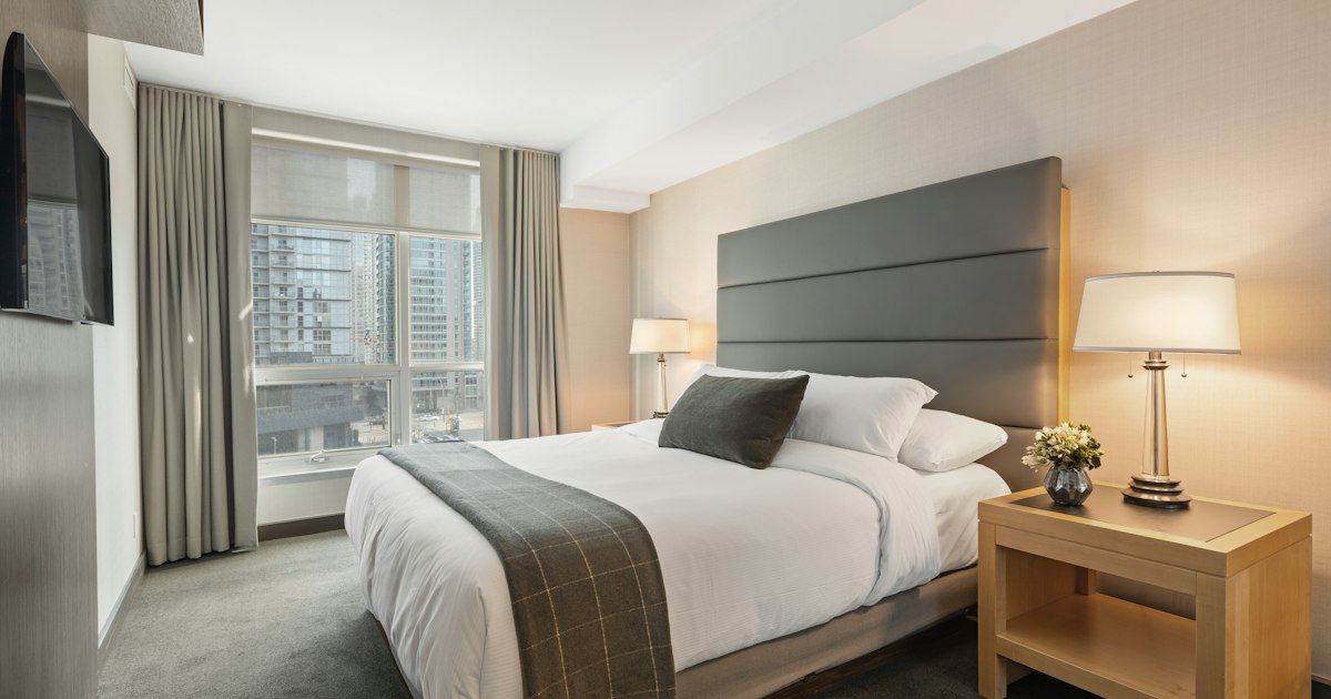 Contemporary hotel guest room with king bed, neutral decor, and floor-to-ceiling windows